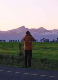 Rear view of man standing on field against sky