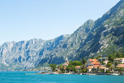 Houses by sea and mountains against clear sky at kotor bay against sky