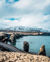 Scenic view of sea by snowcapped mountain against sky