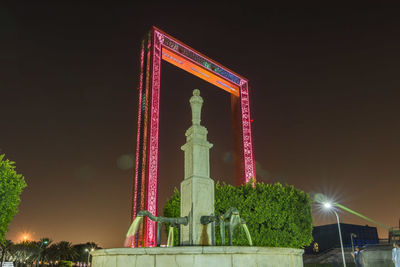 Low angle view of statue against illuminated building at night