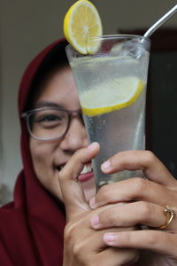 Close-up portrait of smiling woman holding lemonade