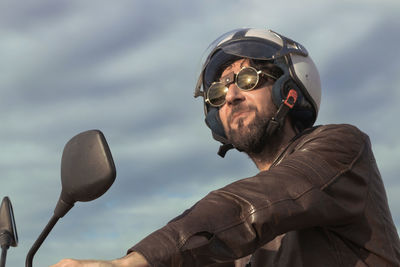 Man wearing sunglasses while riding motorcycle against sky