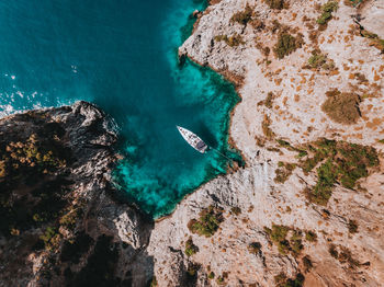 Directly above shot of yacht on sea by rock formation