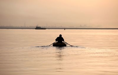 Silhouette man sailing in sea against sky