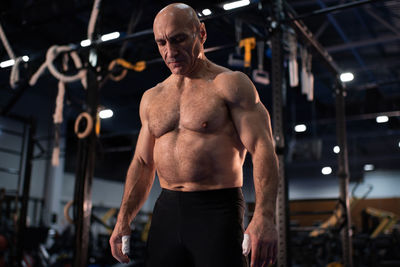 Muscular old sportsman resting in gym