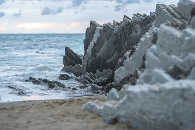 Scenic view slate stones on an beach with sea against sky