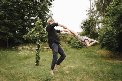 Father swinging daughter in garden