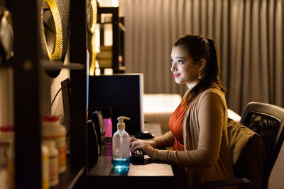 Side view of woman sitting at home