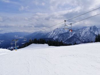 Overhead cable cars over snowcapped mountains against sky