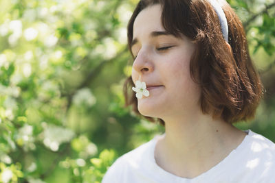 Funny teen girl with bunny ears on easter egg hunt in sunny spring garden