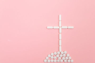 Close-up of cross against pink background
