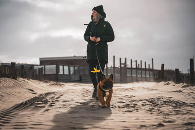 Rear view of man with dog standing at beach