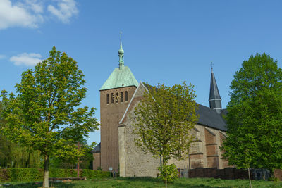 View of tower amidst trees and building against sky