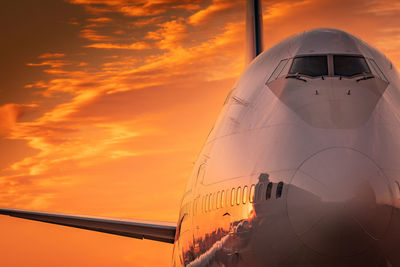 Low angle view of airplane against sky during sunset