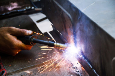 Cropped hand of mechanic welding metal in workshop