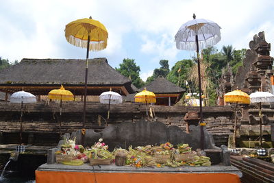 Religious offerings and umbrellas at historic temple against sky