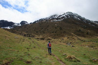 Rear view of woman walking on mountain against sky