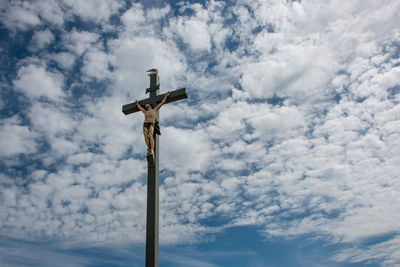 Low angle view of cross on street against sky