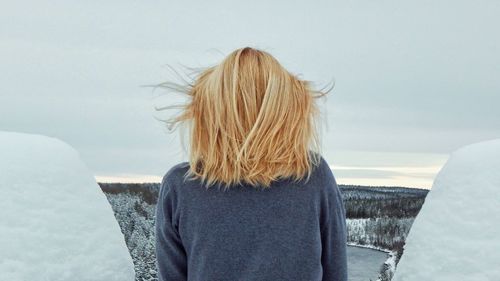 Rear view of woman standing against sea during winter