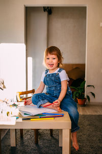 Small child at home at the children's table draws with felt-tip pens.