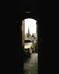 Buildings in city against sky seen through archway