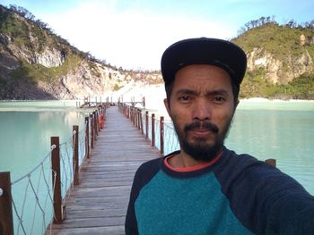 Portrait of man standing by lake against sky