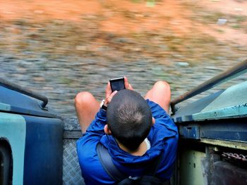 Directly above shot of boy using mobile phone at entrance of train