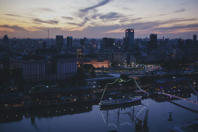 Aerial view of river amidst buildings against sky during sunset