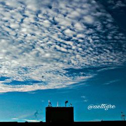 High section of silhouette people against cloudy sky