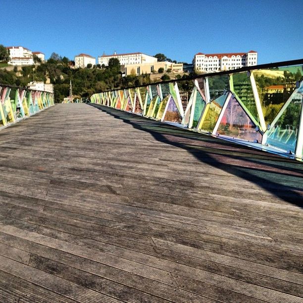 architecture, built structure, building exterior, the way forward, clear sky, bridge - man made structure, diminishing perspective, connection, transportation, railing, blue, sky, sunlight, bridge, city, shadow, day, vanishing point, surface level, footbridge