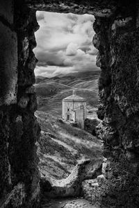 Built structure on landscape against cloudy sky
