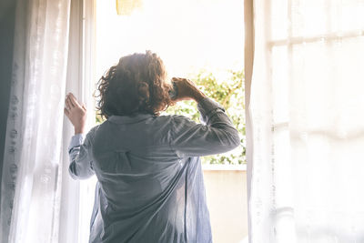 Rear view of man standing by window