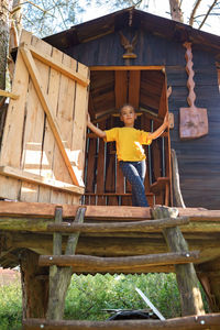 Girl plays in creative handmade treehouse in backyard, summer activity, happy childhood, cottagecore