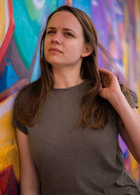 Portrait of young woman standing against wall