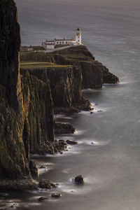 Aerial view of lighthouse on rock formation by sea