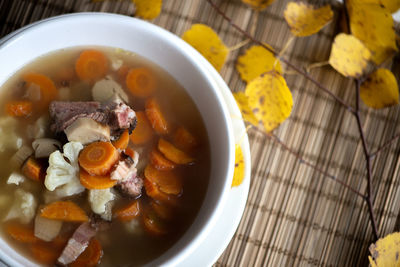 An overhead photo of a plate mushroom soup with boletus decorated with colorful autumn leaves