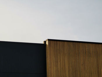 Modern architectural details, wooden wall and black metal wall against sky.