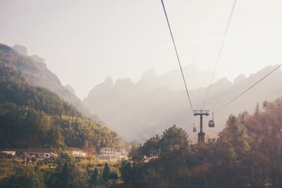 Overhead cable cars over mountains against sky
