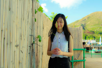 Portrait of beautiful young woman standing against sky