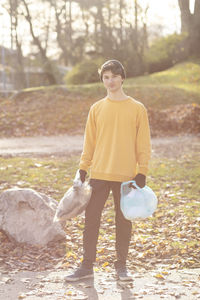 Portrait of male volunteer collecting garbage while standing in park