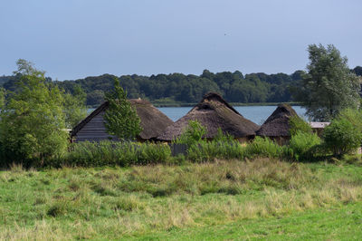 Built structure on field by trees against sky