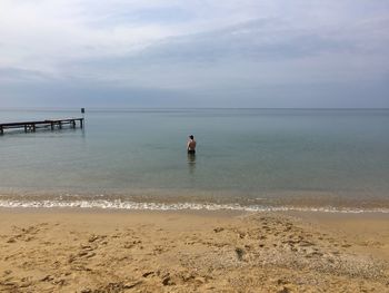 Rear view of man standing on beach against sky