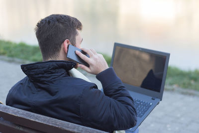 Rear view of man using mobile phone