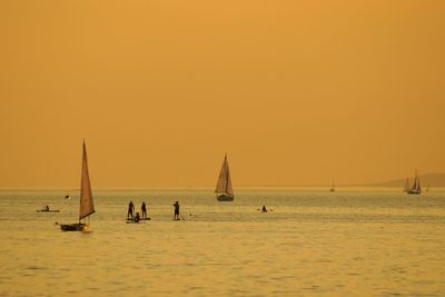 Silhouette sailboat sailing on sea against clear sky during sunset