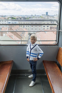 Full length of a boy standing against built structure