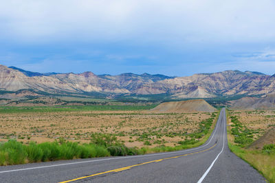 Road leading towards mountains against sky