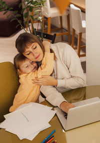 Working mom works from home office with kid. woman using laptop. child drawing. woman freelancer