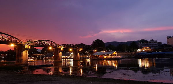 Illuminated bridge over river against sky at night