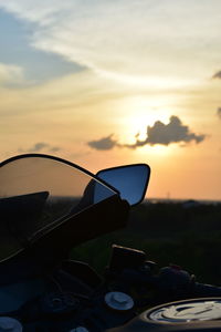 Close-up of sunglasses against sky at sunset