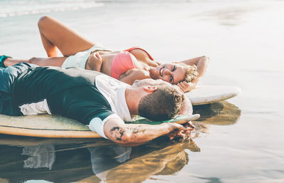 Happy friends lying on surfboards at beach